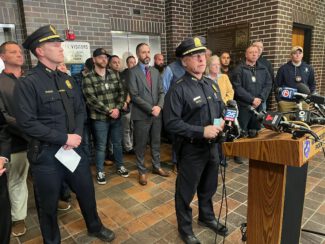 Members of the Worcester Police Department and city officials listen as Interim Police Chief Paul Saucier speaks to members of the news media at a press conference Monday night at the Worcester Police Department (photo by Walter Bird)