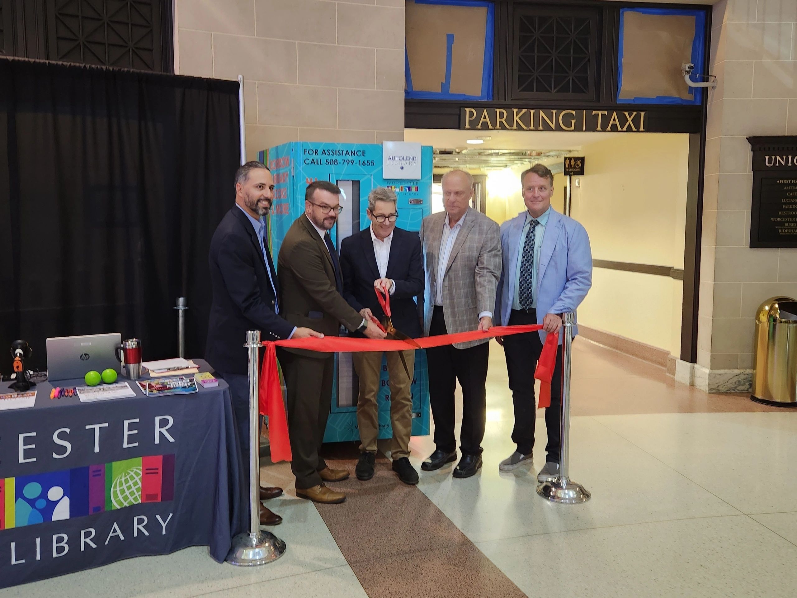 Left to right are City Manager Eric Batista; Jason Homer, executive director of the Worcester Public Library; Robert Favini, head of Library Advisory & Development/Government Liaison for the Massachusetts Board of Library Commissioners; Mayor Joe Petty; Senator Mike Moore at the Union Station WPL vending machine ribbon cutting (photo via WPL)
