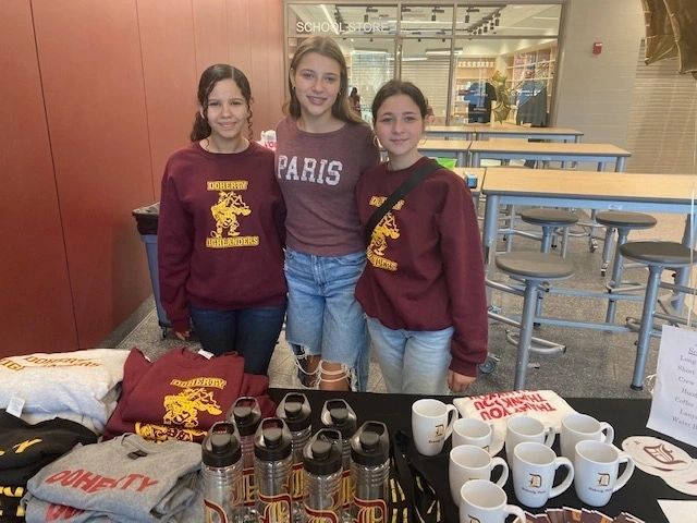 Freshmen Anna Fernandes, Isabella Emely and Ella Orciuch at the merchandise table on the morning of the open house (photo credit: Rod Lee)
