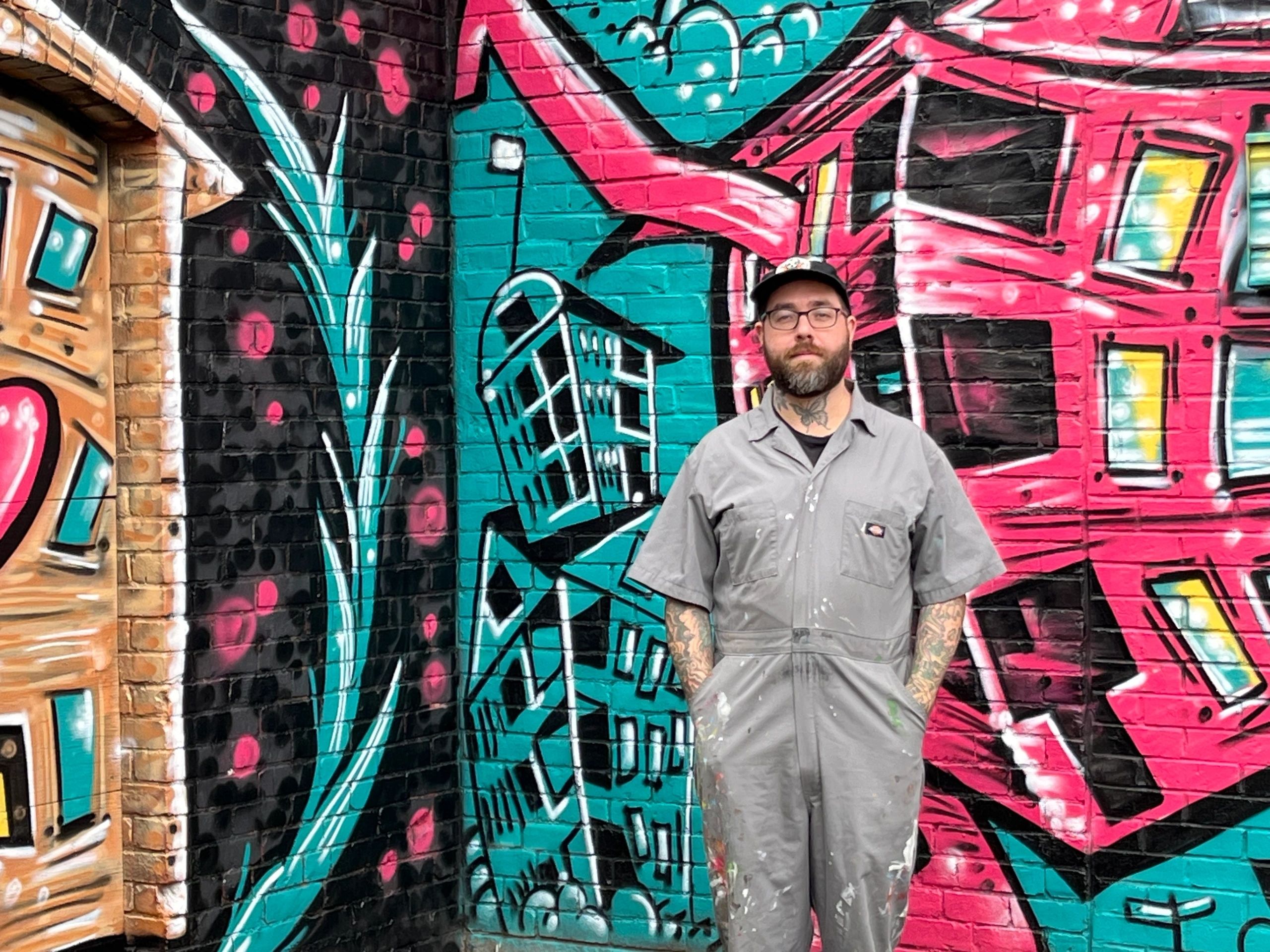 Artist Eamon Gillen stands in front of his mural painted on the Hotel Vernon building in Kelley Square (Photo by Kiernan Dunlop)