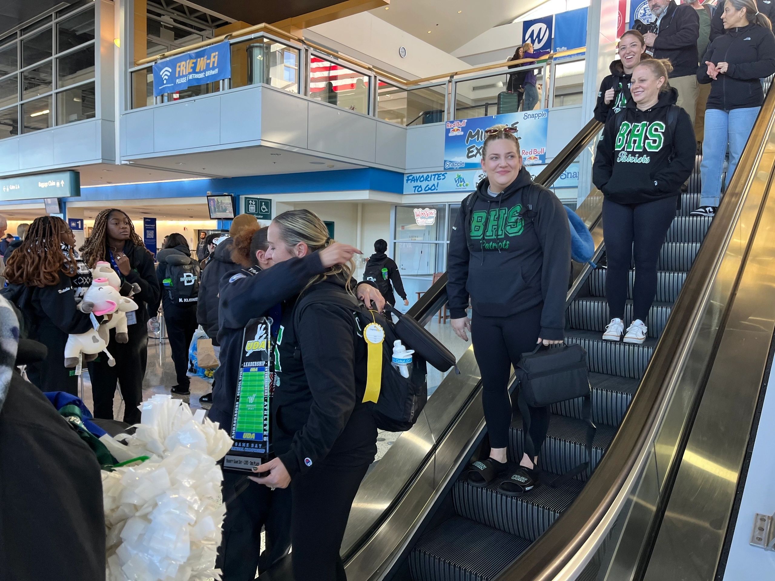 Burncoat Dance Coach Kellie Shea holding a trophy the Spirit Program won at a national competition and greeting the crowd that welcomed the program home at Worcester Regional Airport. 