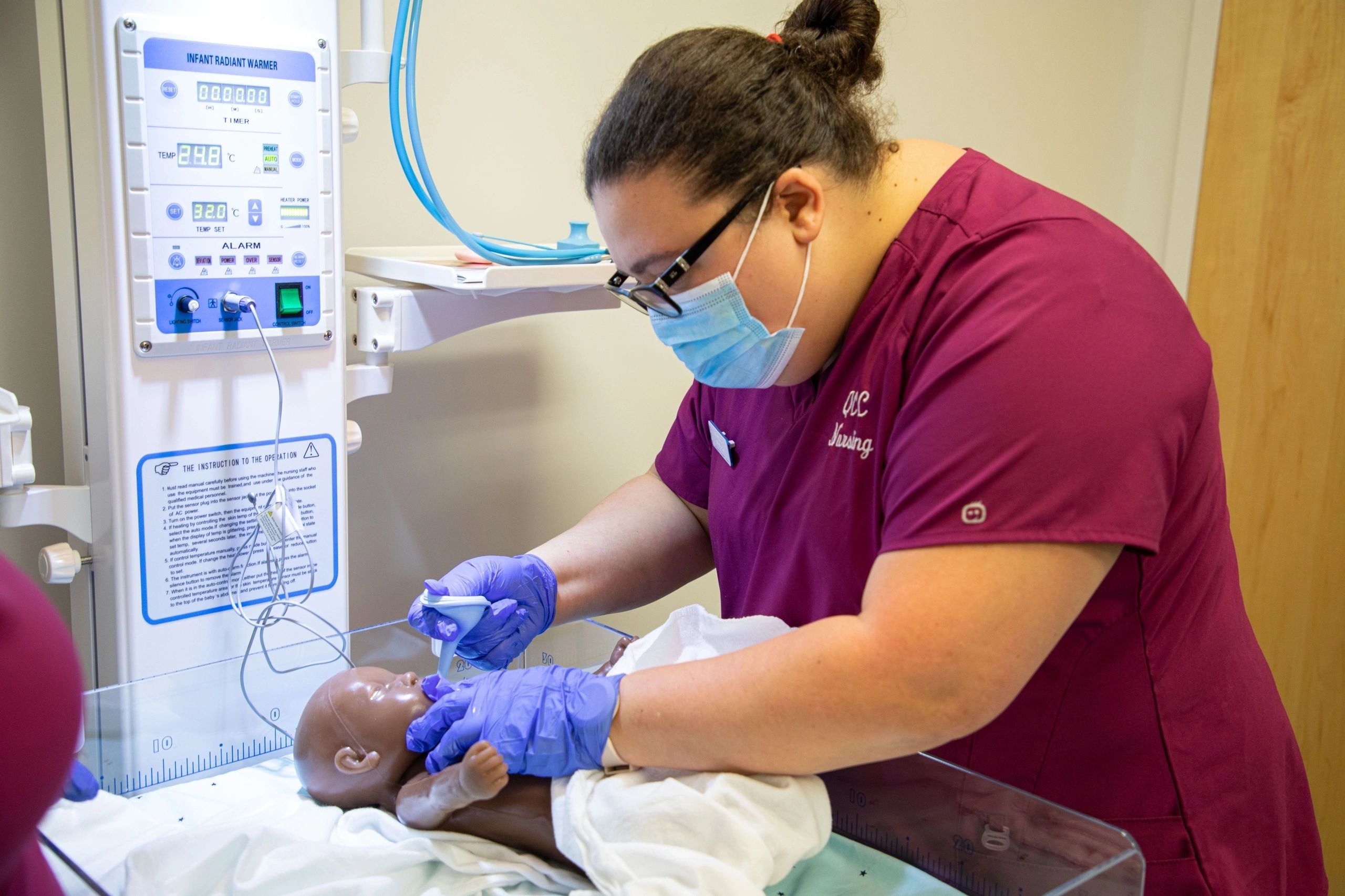 Mariseliz Heredia, 2024 nursing graduate student, works with maternity simulation equipment (photo courtesy QCC)