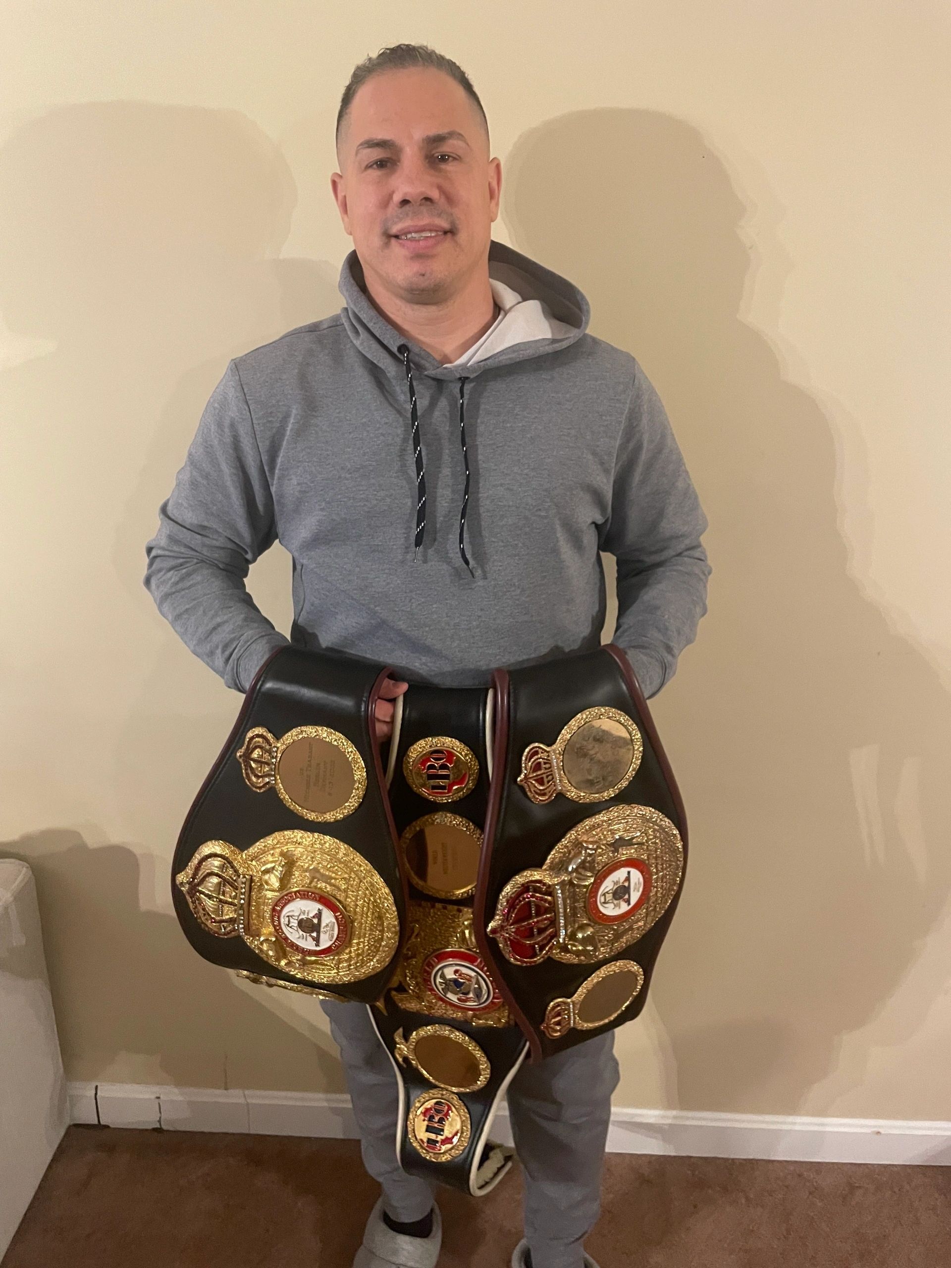 Jose Antonio Rivera holds his three world championship boxing belts in his Worcester home (photo by Bill Doyle)