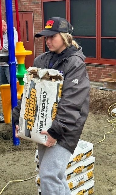 Kylie Hampton carrying a 40 lb bag of concrete mix (photo submitted)