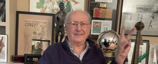 Bob Cousy sits at his home in front of the Bob Cousy Collegiate Point Guard of the Year Award (left) and the Bob Cousy Trophy (right) that has been awarded to the NBA Eastern Conference champions since 2022 (photo by Bill Doyle)