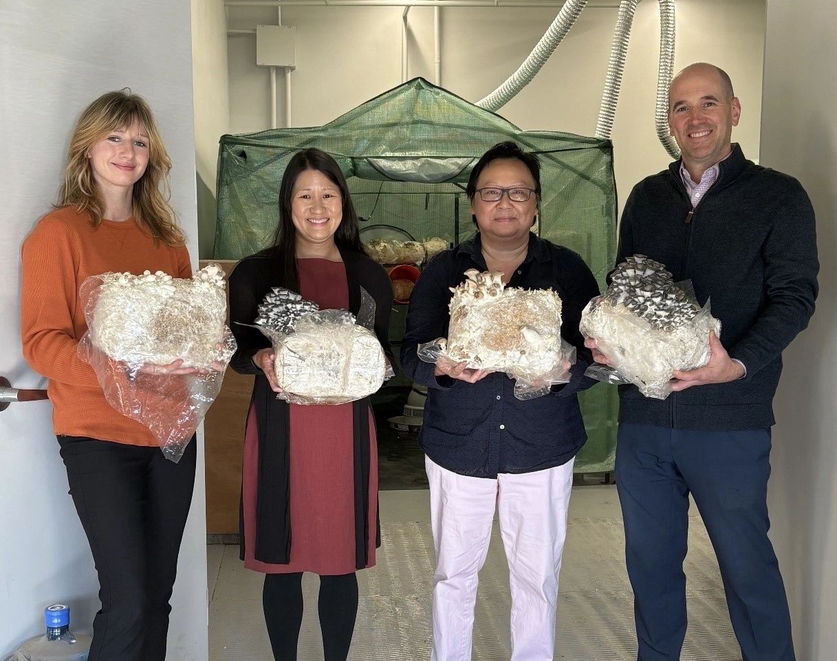 Holding mushroom blocks in front of the Southeast Asian Coalition’s growing room are