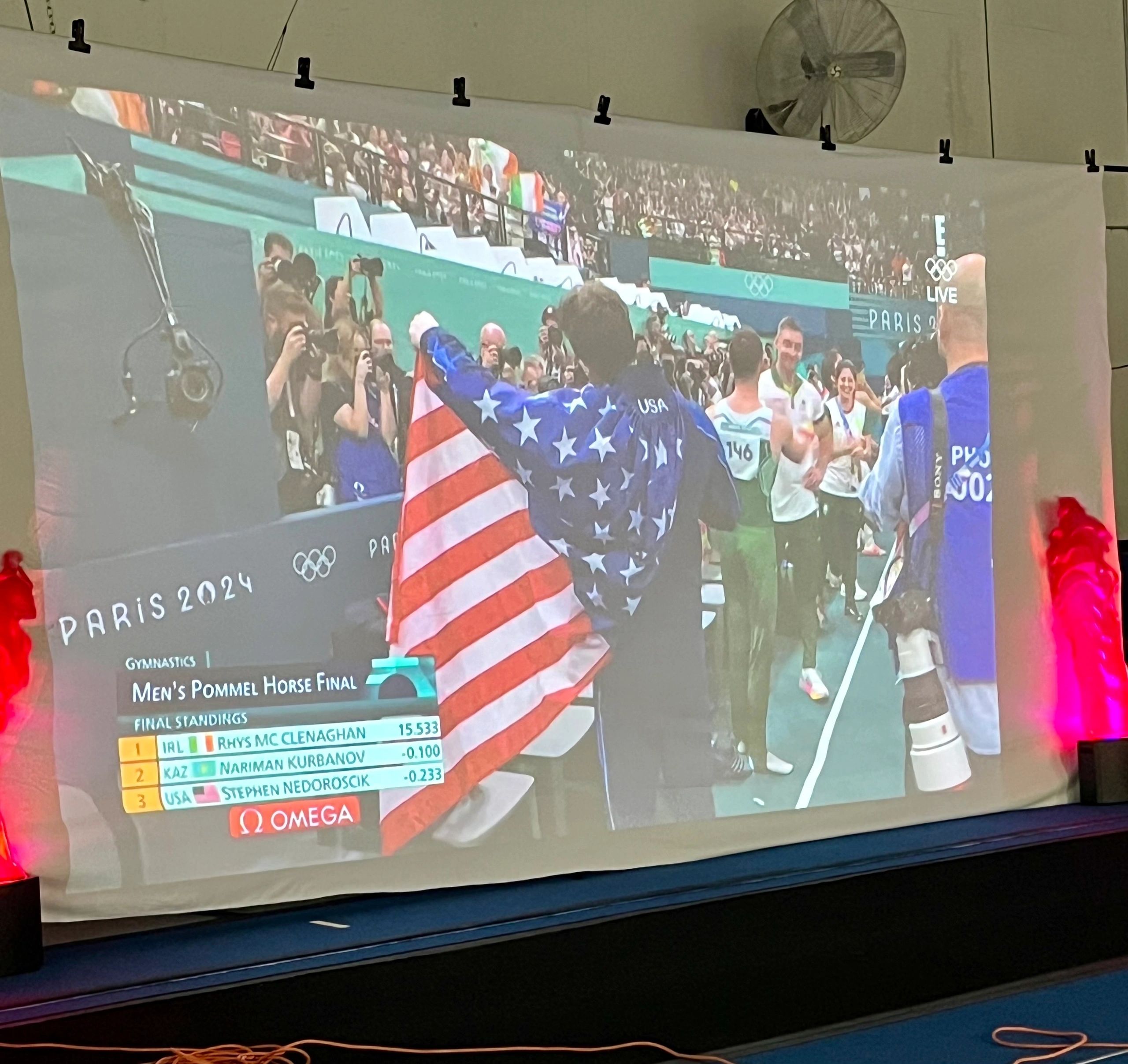 The video of Stephen Nedoroscik celebrating his bronze medal is projected onto a screen at the Sterling Academy of Gymnastics. (Mike Vigneux photo)