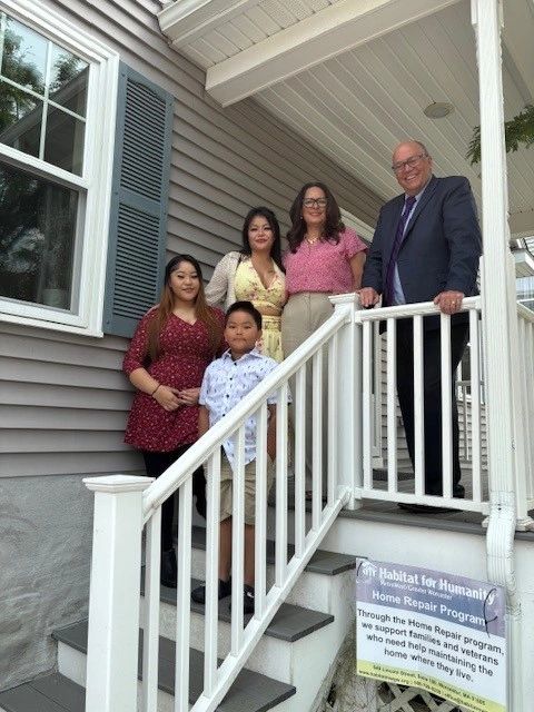 The Lor family stand on the steps of their new home (along with Unibank's Michael Welch and Tania Medina)