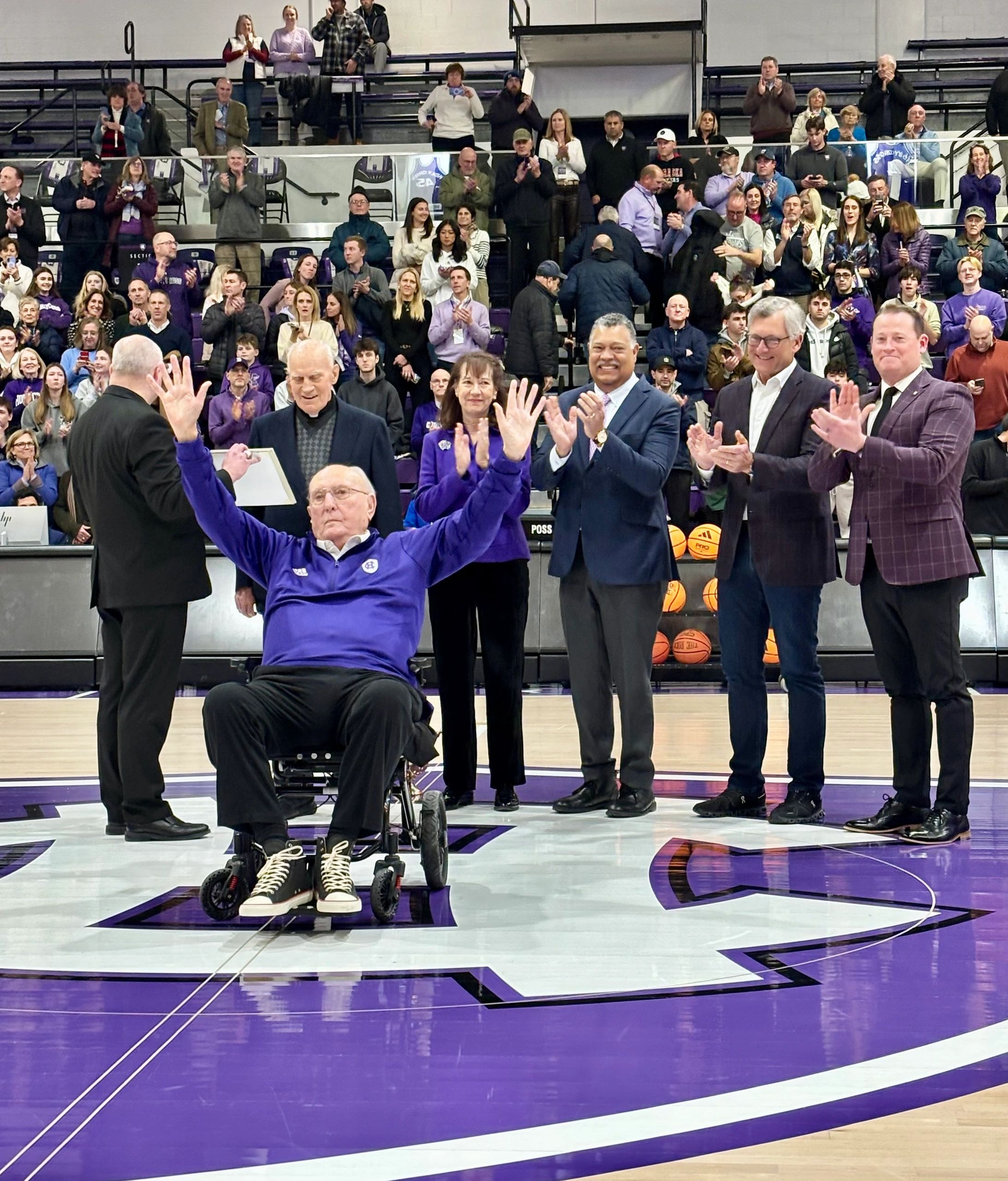 Bob Cousy waves to the crowd. Behind him are Father Earle Markey with pad, Vousy’s daughter Ticia, Holy Cross president Vincent Rougeau, former member of the HC board of trustees Bob Atchinson and HC VP of Intercollegiate Athletics Kit Hughes (photo by Bill Doyle)